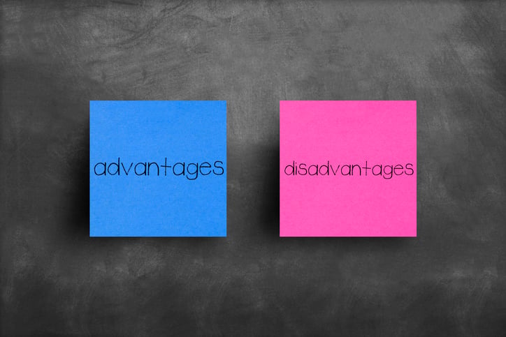 photo of a blue and pink postit note, blue says advantages, pink says disadvantages